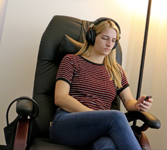 Female student with headhphones in reclining chair at UT